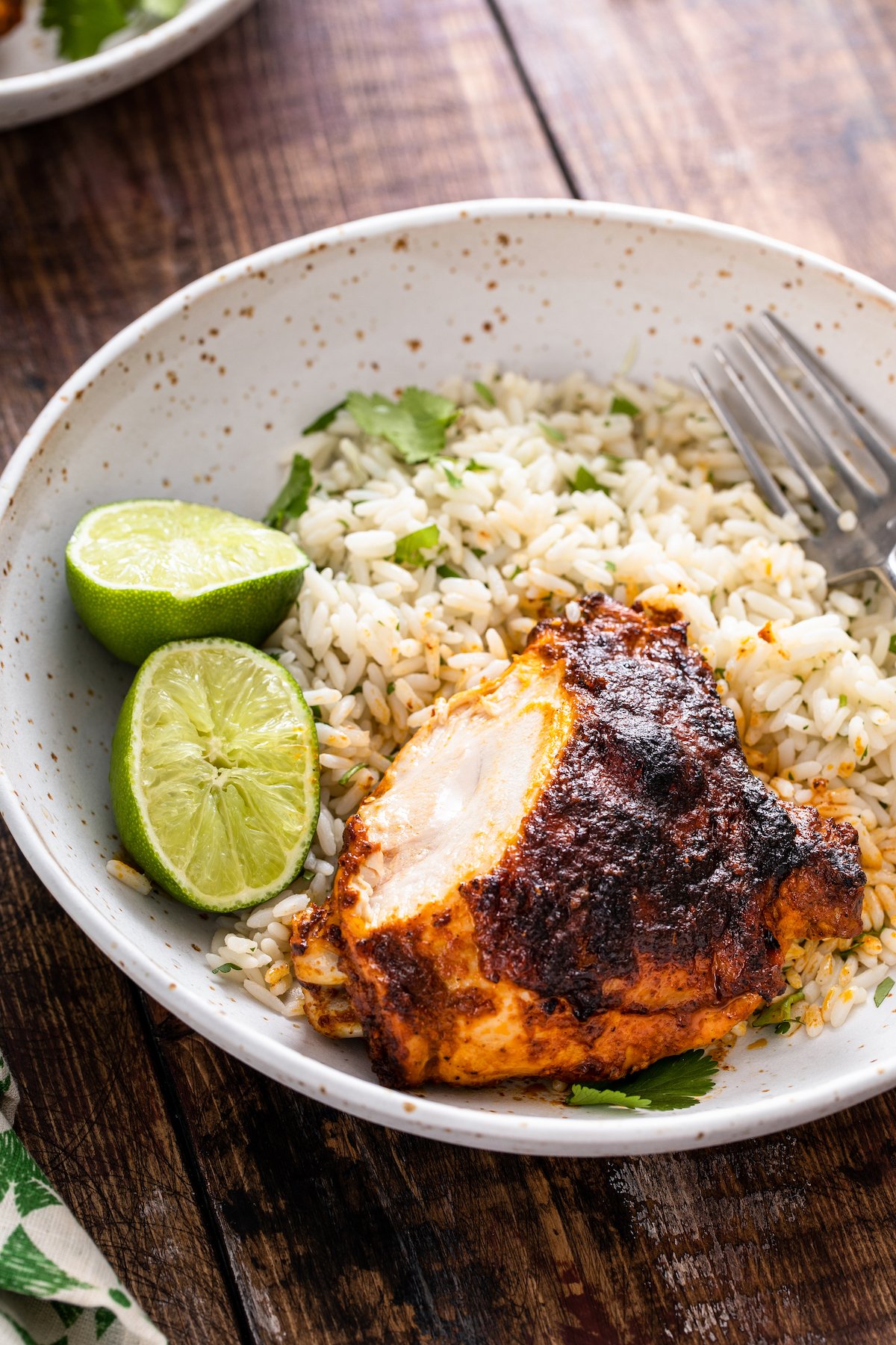 Sliced pollo asado served with rice, cilantro, and lime wedges.