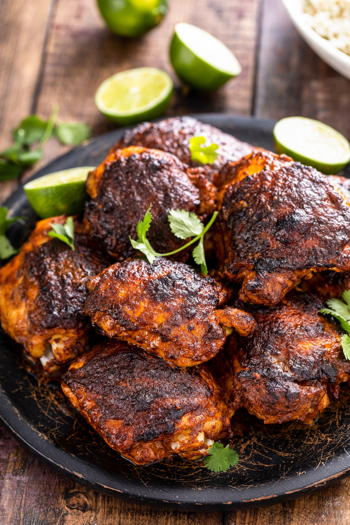 Pollo asado on a plate with cilantro and lime wedges.