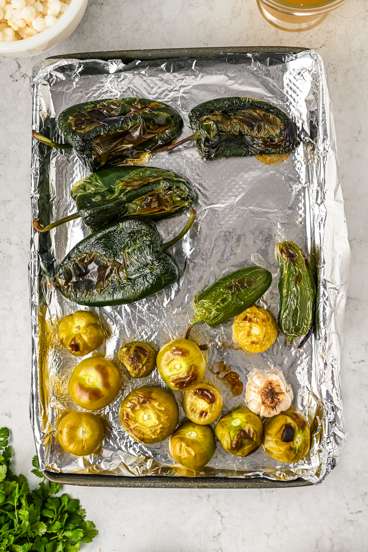 Charred poblanos, tomatillos, and jalapeños in the baking tray.