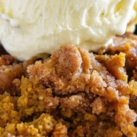 Pumpkin crisp in a bowl with vanilla ice cream on top.