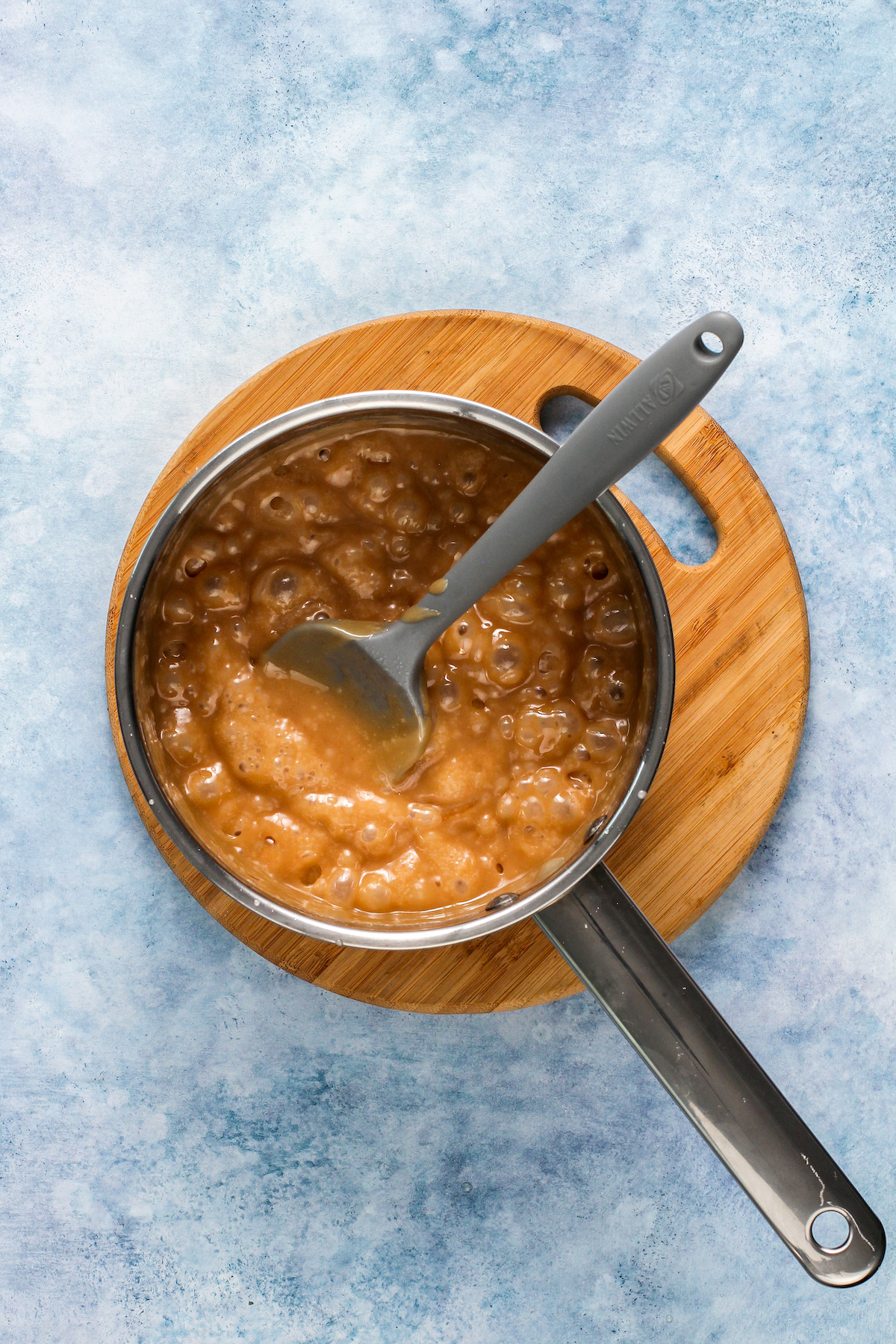Caramel mixture in a sauce pan on a trivet.