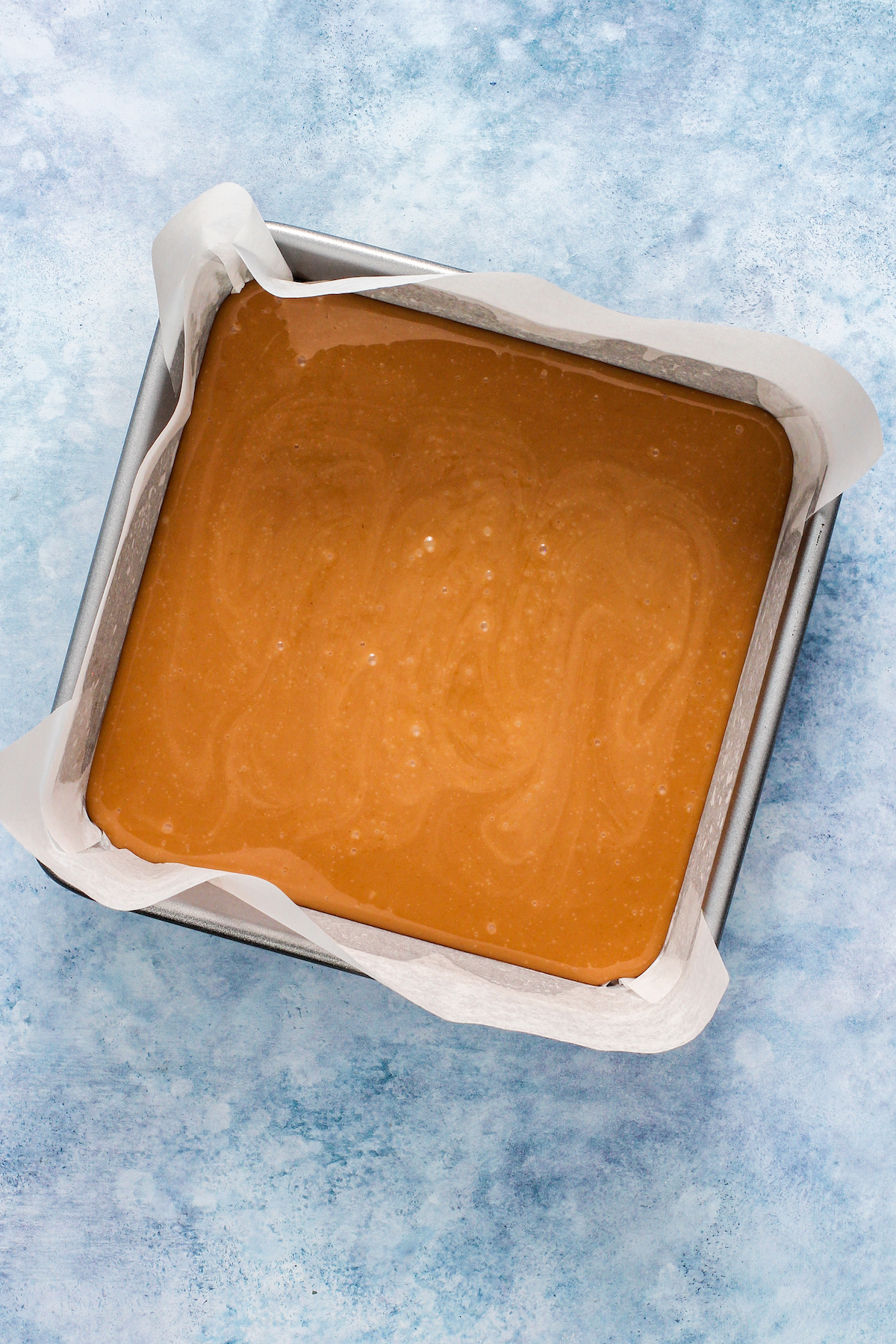 Caramel poured into a baking pan lined with parchment paper.