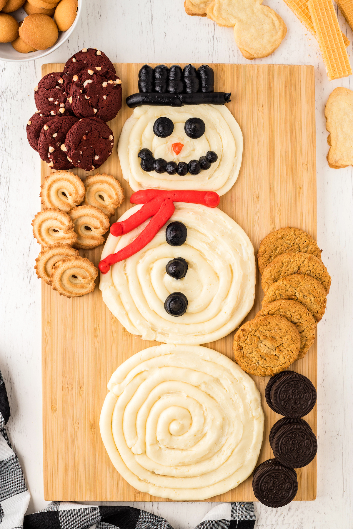 Adding cookies to a snowman buttercream board.