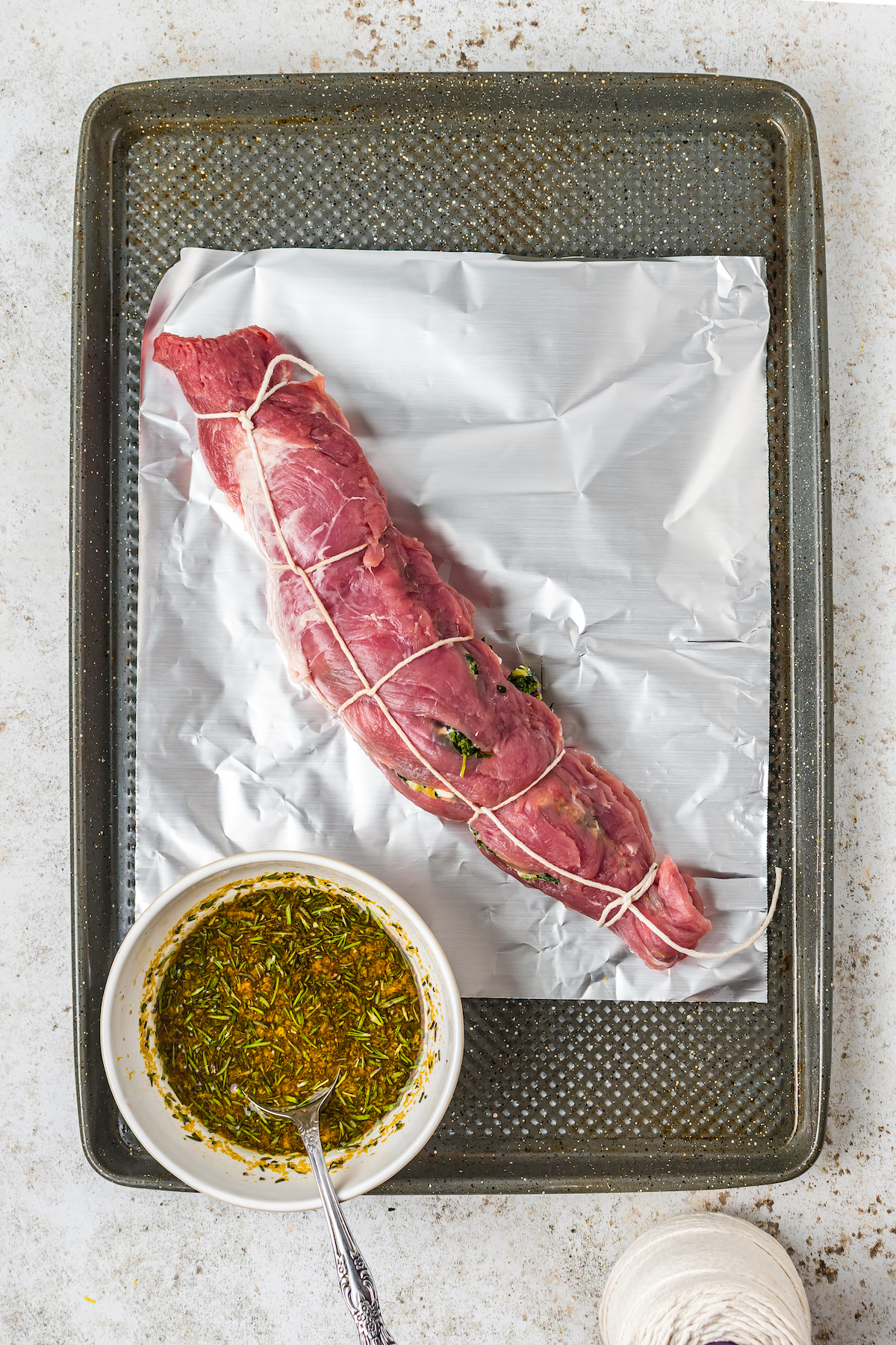 Placing the rolled pork loin over a piece of foil in a baking sheet.