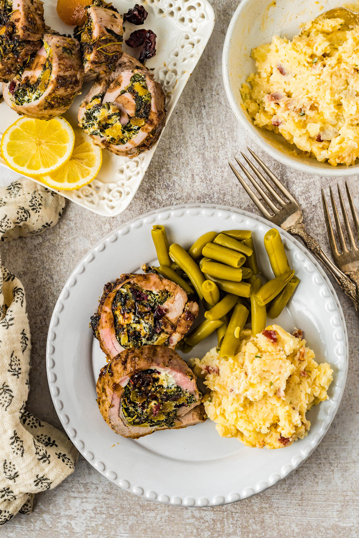 Stuffed pork loin with mashed potatoes and green beans.