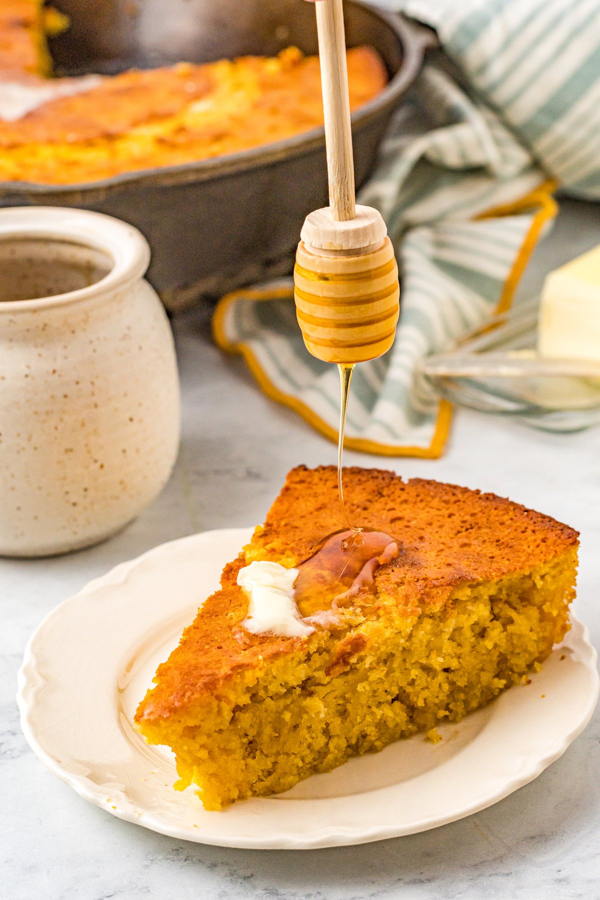 Slice of sweet cornbread with butter and a drizzle of honey. 
