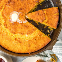 Sliced sweet cornbread in the skillet with a knob of butter.
