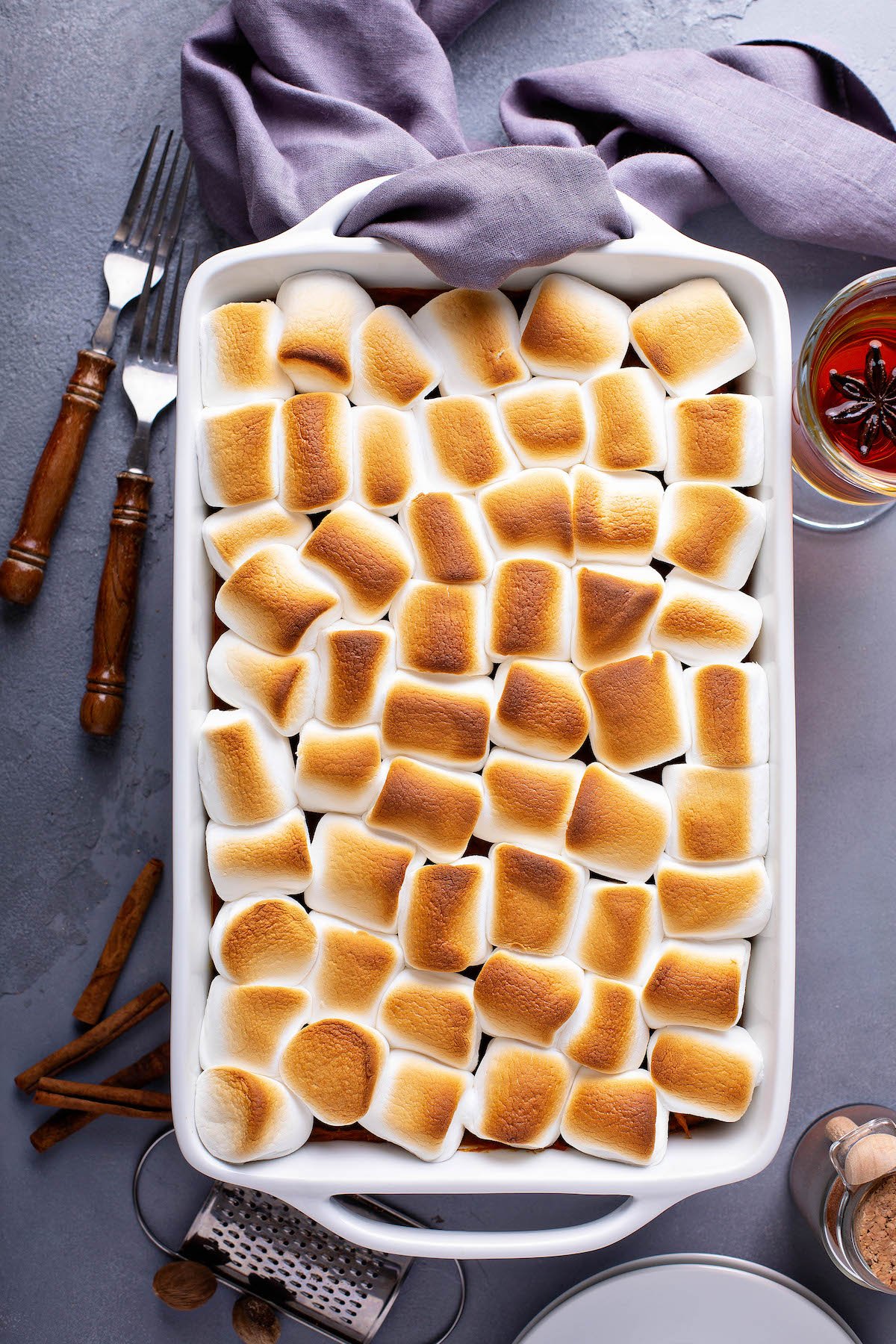 Toasted marshmallows layered on top of sweet potatoes in a casserole dish.