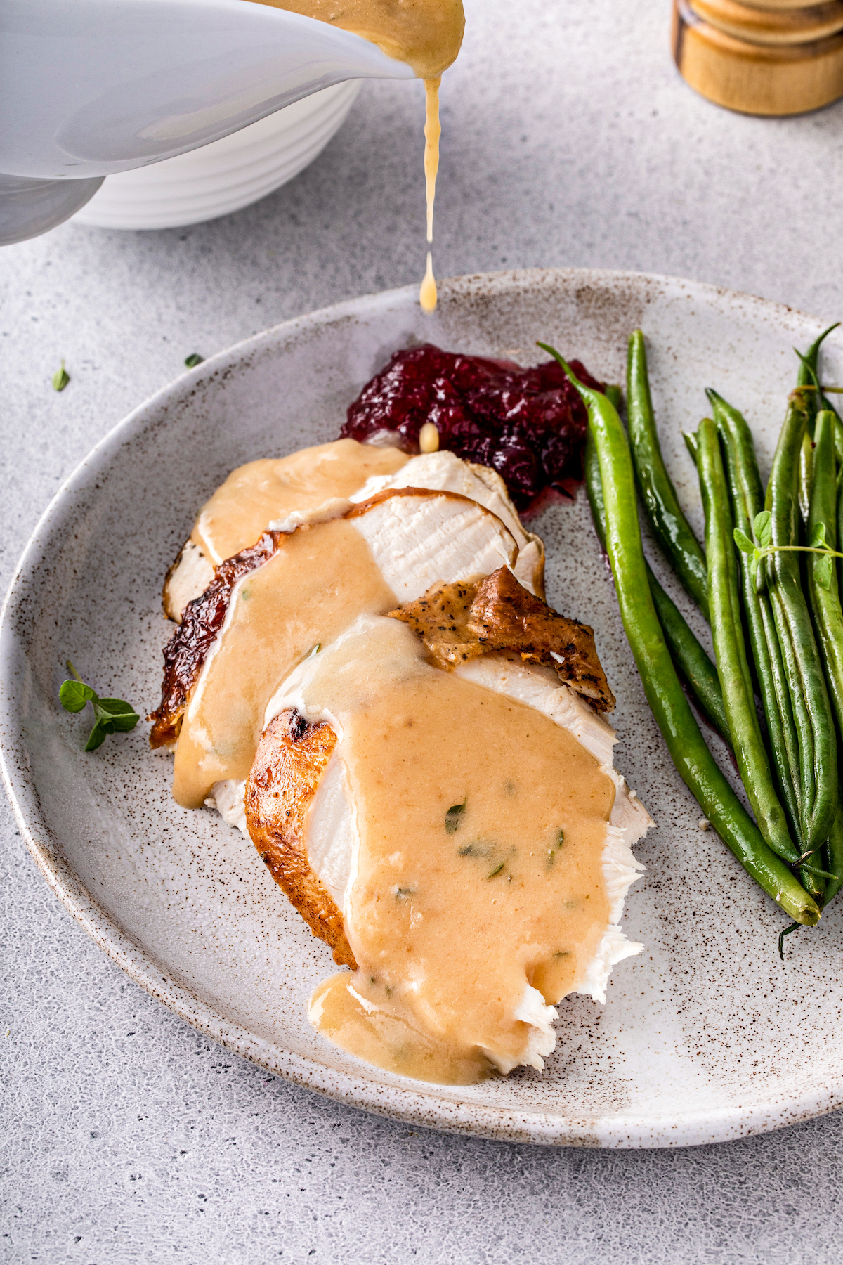 Sliced turkey on a dinner plate, topped with homemade gravy.