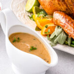 Turkey gravy next to a whole roast turkey.