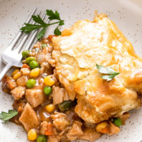 Turkey pot pie with puff pastry on a plate with a fork.