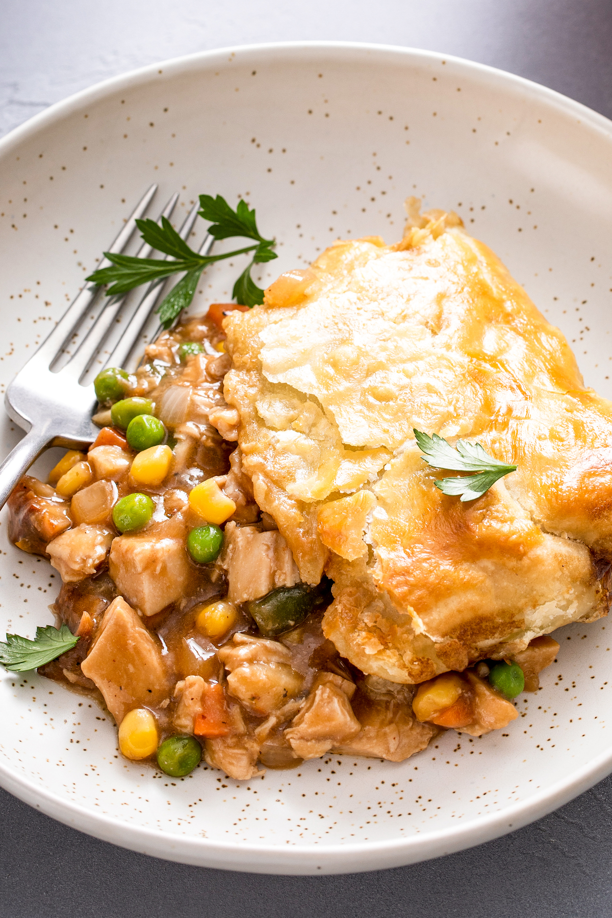 Turkey pot pie with puff pastry on a plate with a fork.