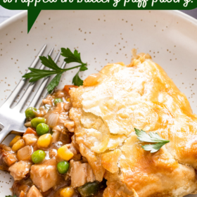 A slice of turkey pot pie with puff pastry on a plate with a fork.