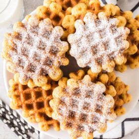 Waffle cookies dusted with powdered sugar on a plate.