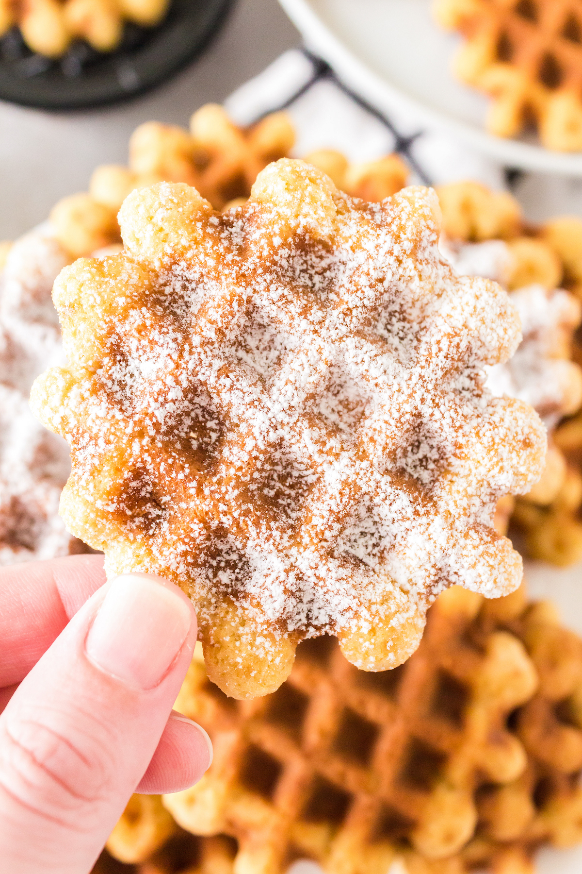 Hand holding up a vanilla waffle cookie.