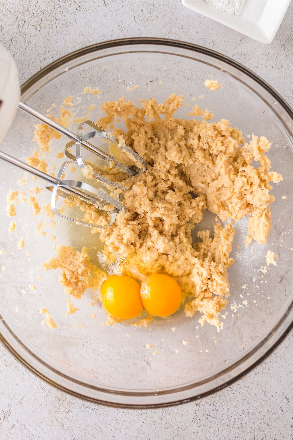 Adding the eggs to the beaten butter and sugar mixture.