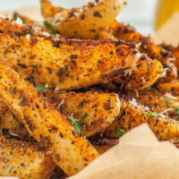 Seasoned air fryer potato wedges in a parchment-lined dish.