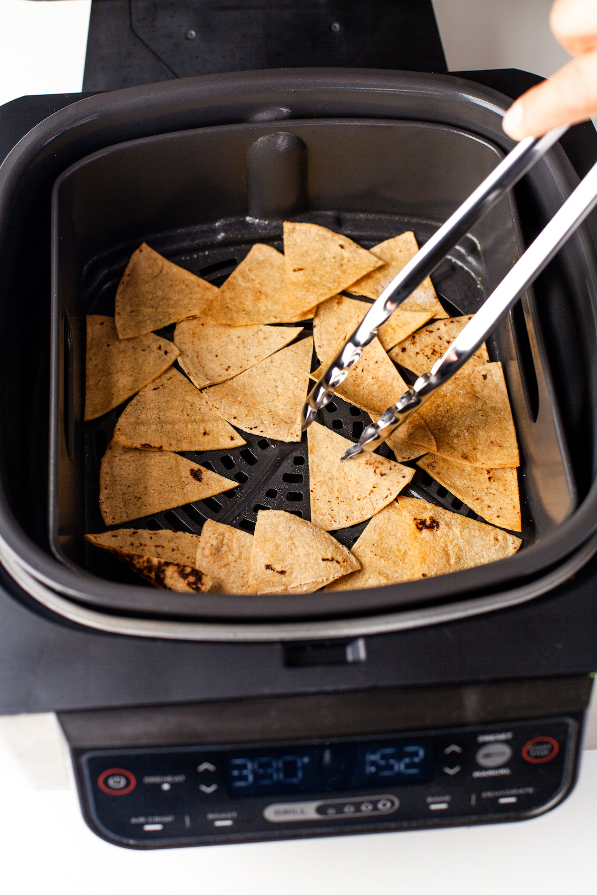 Flipping the tortilla chips over in the air fryer.