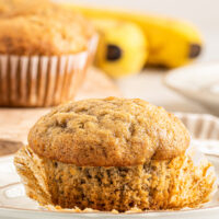 A banana muffin with the muffin liner pulled away from the base.