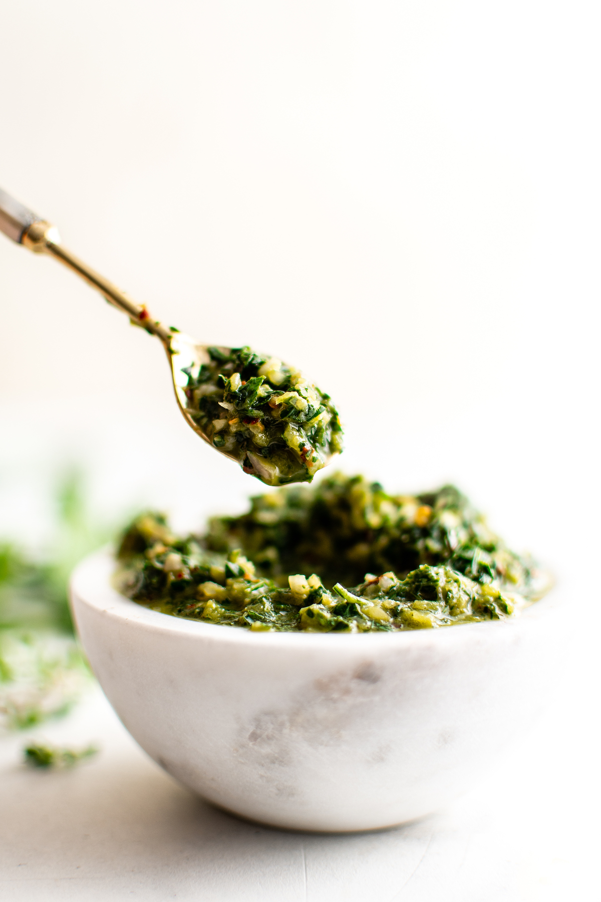 Spoonful of chimichurri over a bowl.