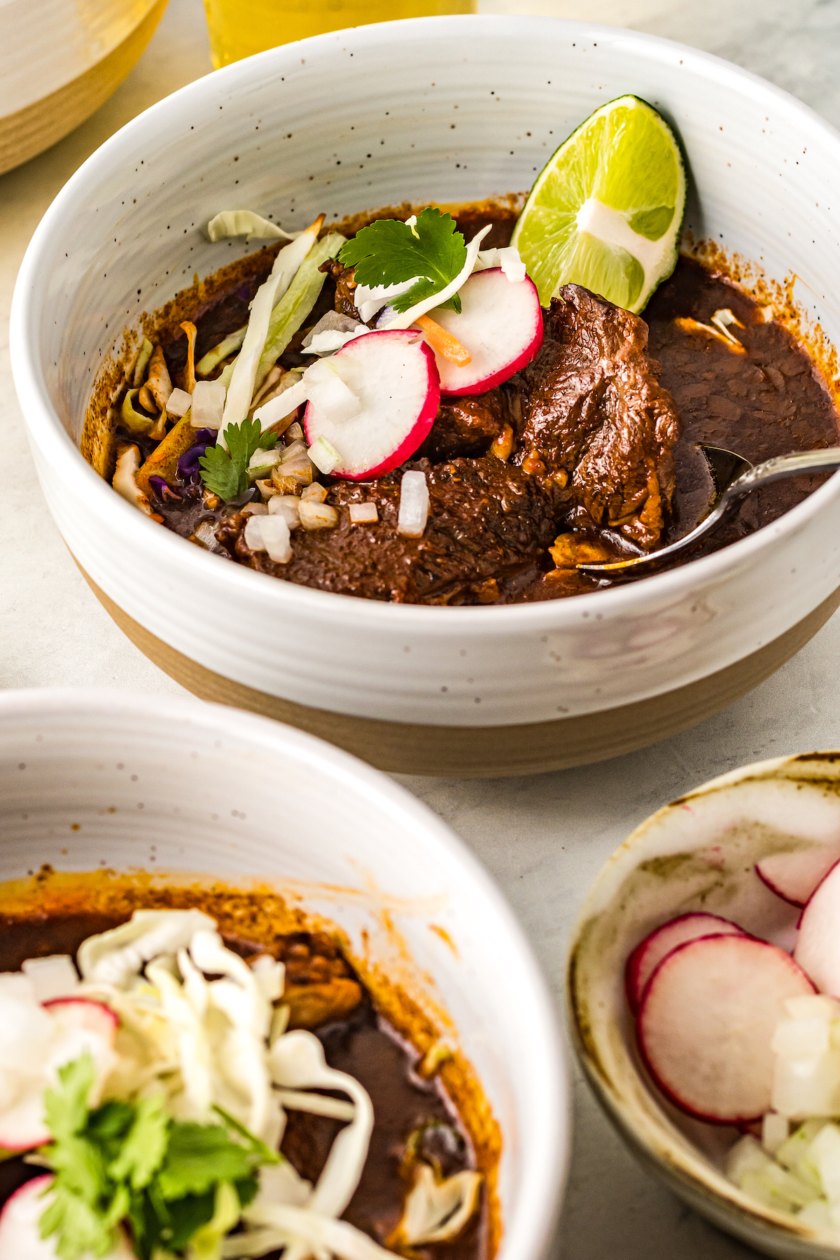 Bowls of beef birria with toppings.