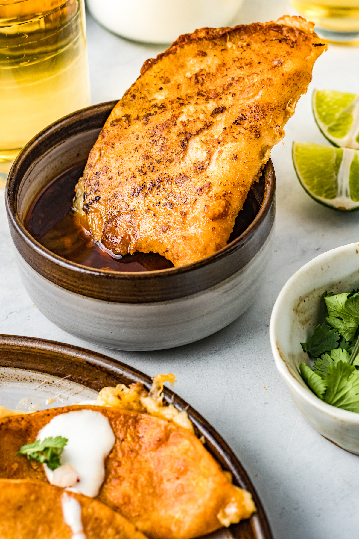 Dipping a taco de birria into consomé.