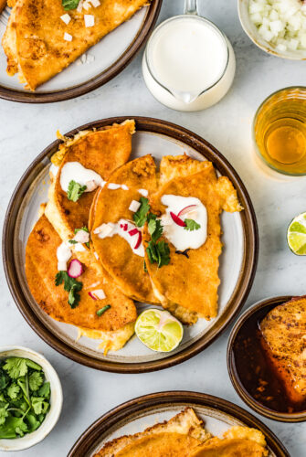 Tacos de birria in a plate topped with crema, cilantro, and onion.
