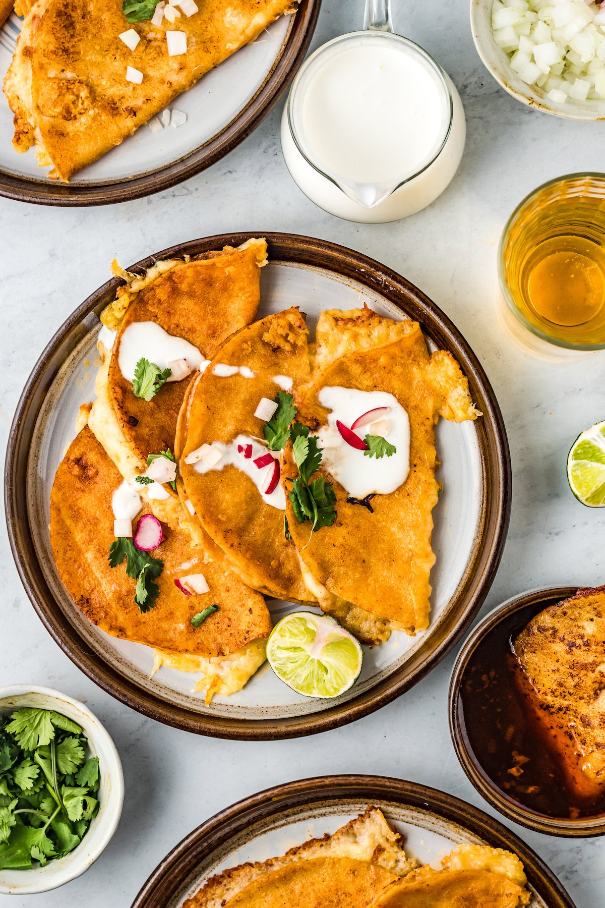 Tacos de birria in a plate topped with crema, cilantro, and onion.