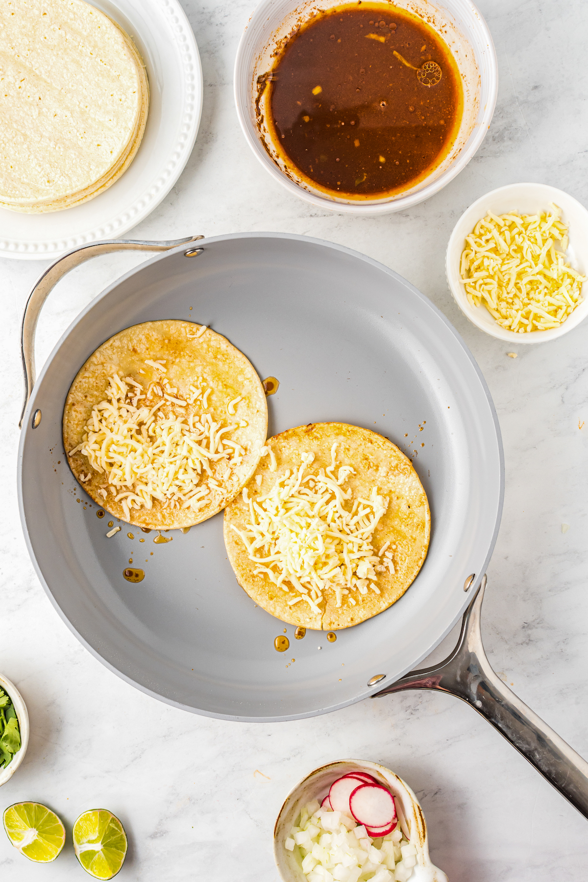 Cheese on one half of tortillas in a pan.