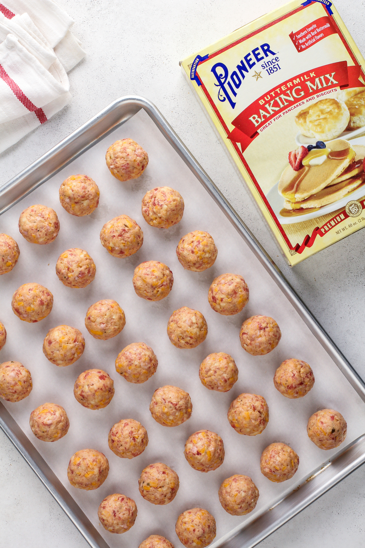 Unbaked sausage balls on a cookie sheet lined with parchment paper.