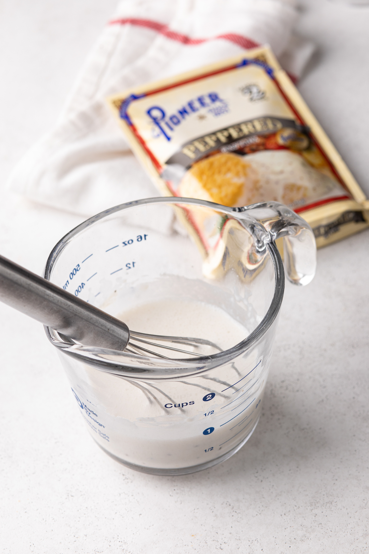 Gravy mix and water in a measuring cup with a whisk.