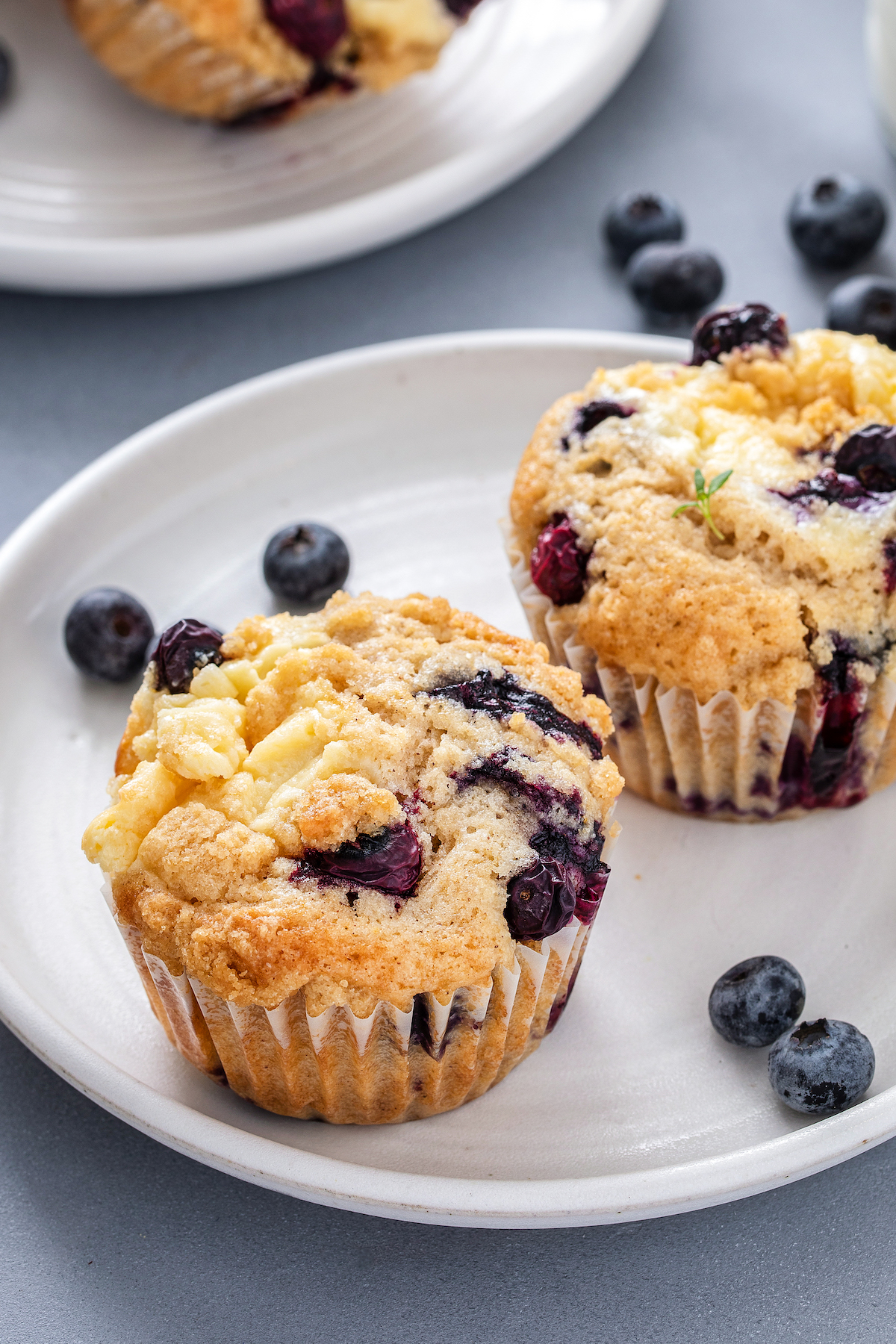 Two blueberry muffins on a small plate.