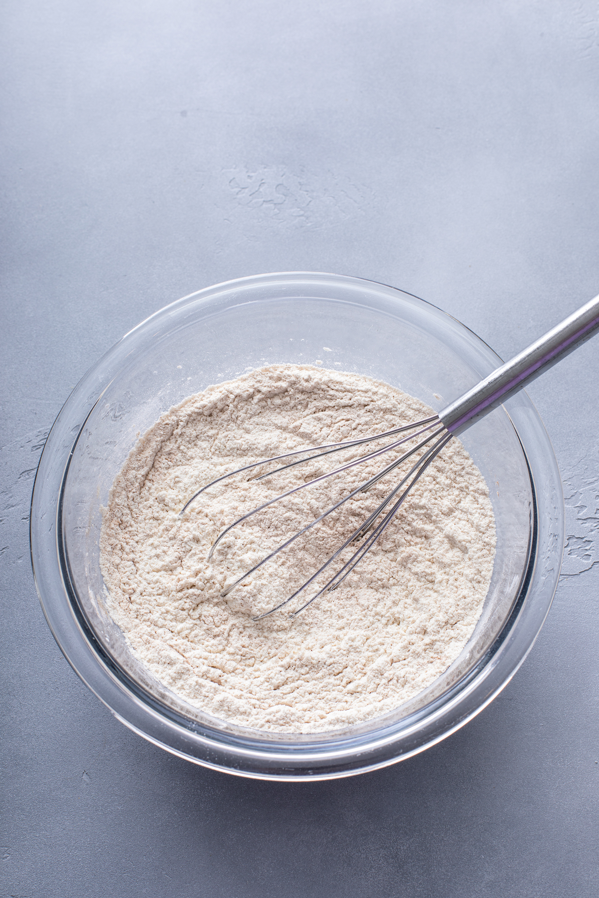 Dry baking ingredients in a glass bowl with a whisk.