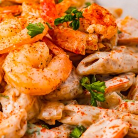 Cajun shrimp pasta with seasoning and fresh herbs on top.