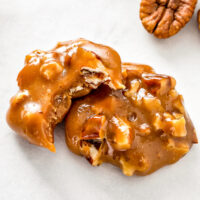 Two pecan clusters stacked on top of each other with a bite taken out of the top pecan candy.