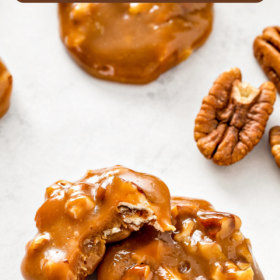 Caramel pecan candy stacked on top of each other on parchment paper.