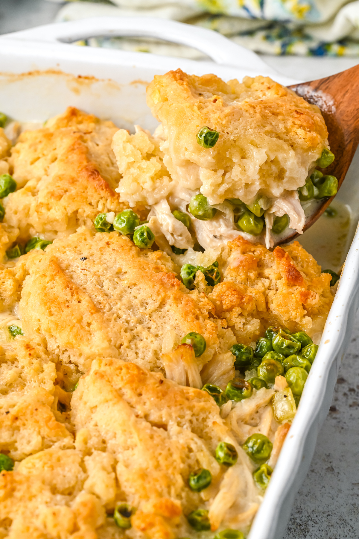 Spooning chicken and dumplings from a casserole dish.