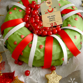 Green grinch cake with red and white ribbons on it.