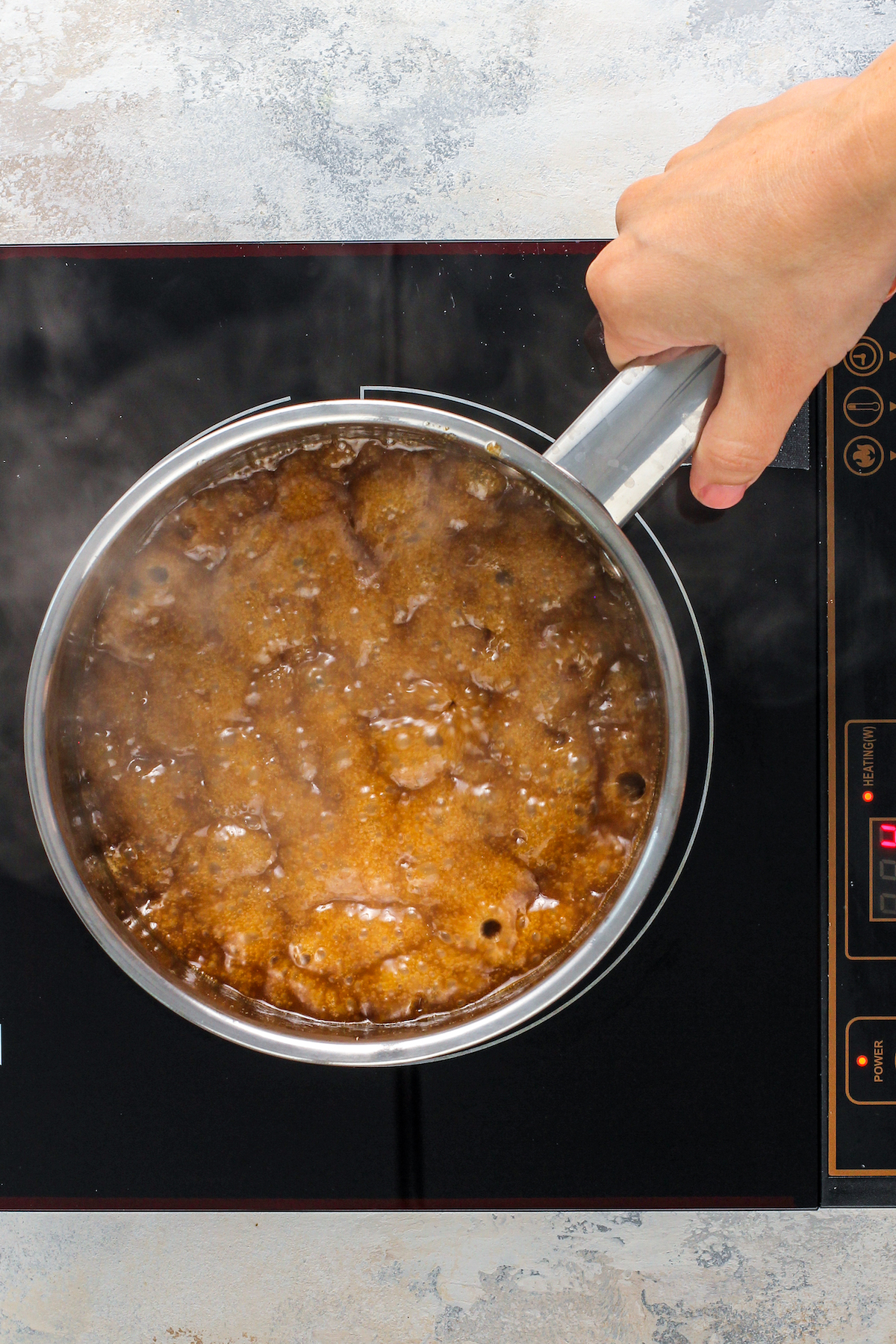 Toffee cooking in a pot on a stove top.