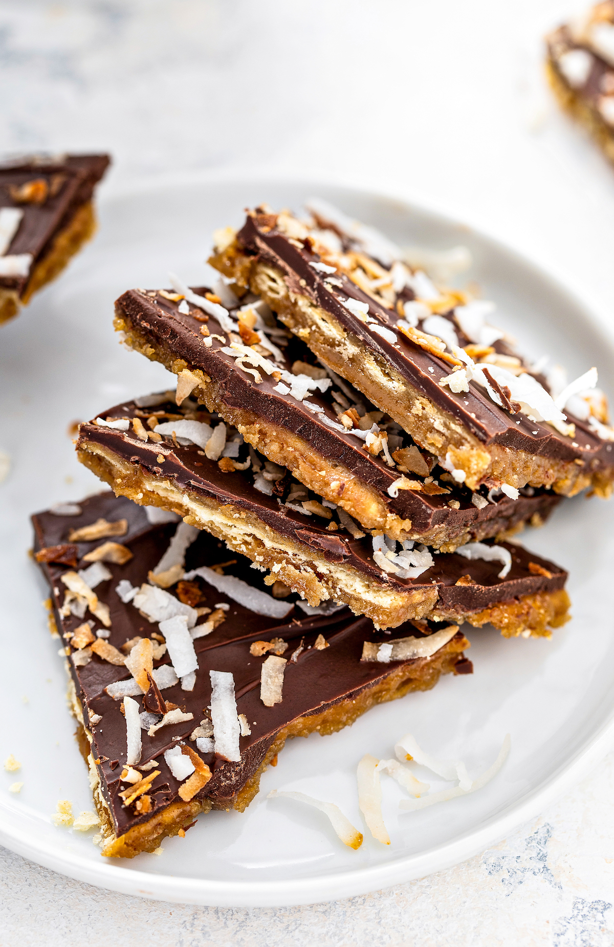 Coconut saltine cracker toffee broken into pieces on a plate.