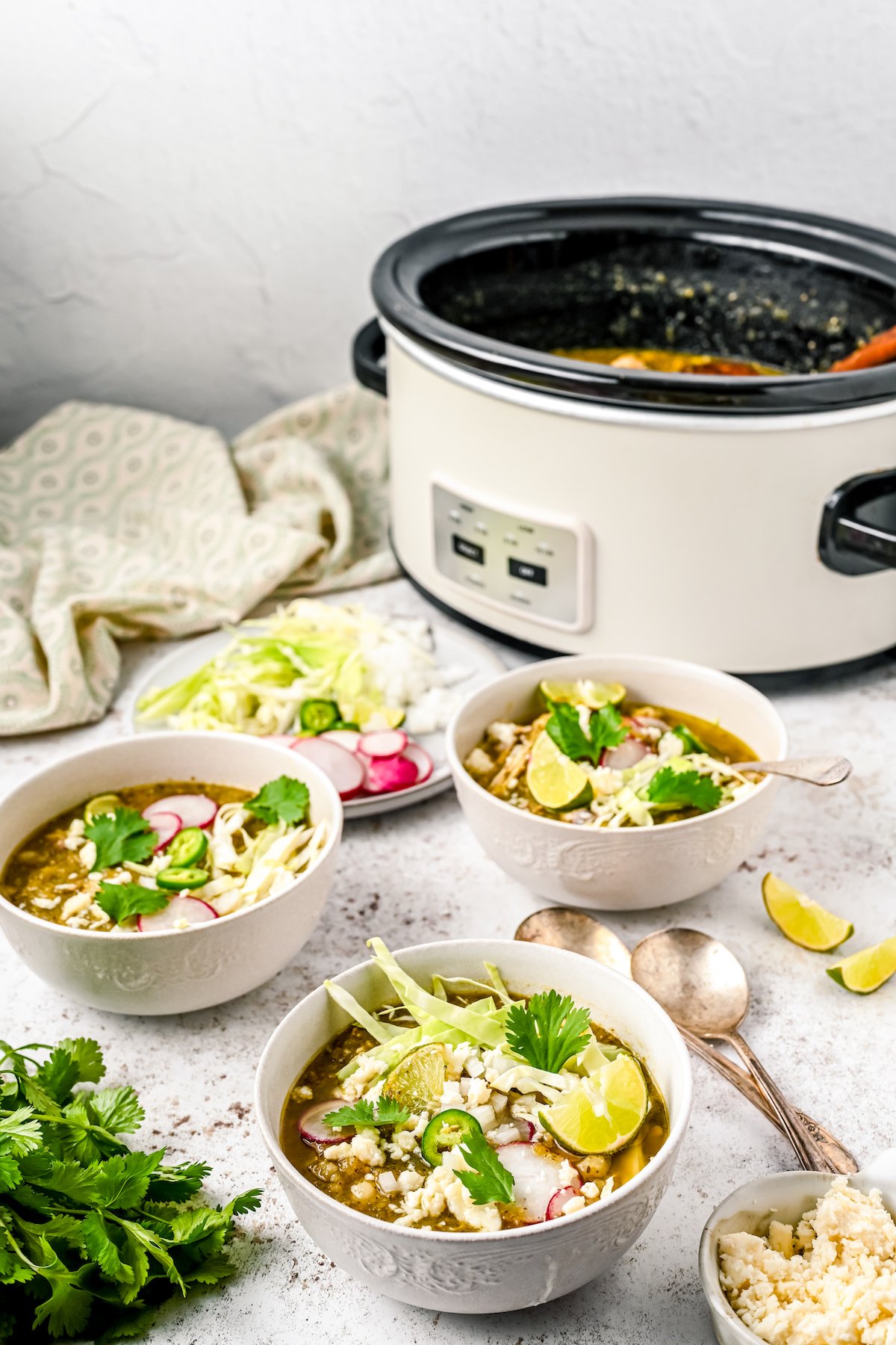 Bowls of Mexican pozole with toppings. The crockpot is in the background.