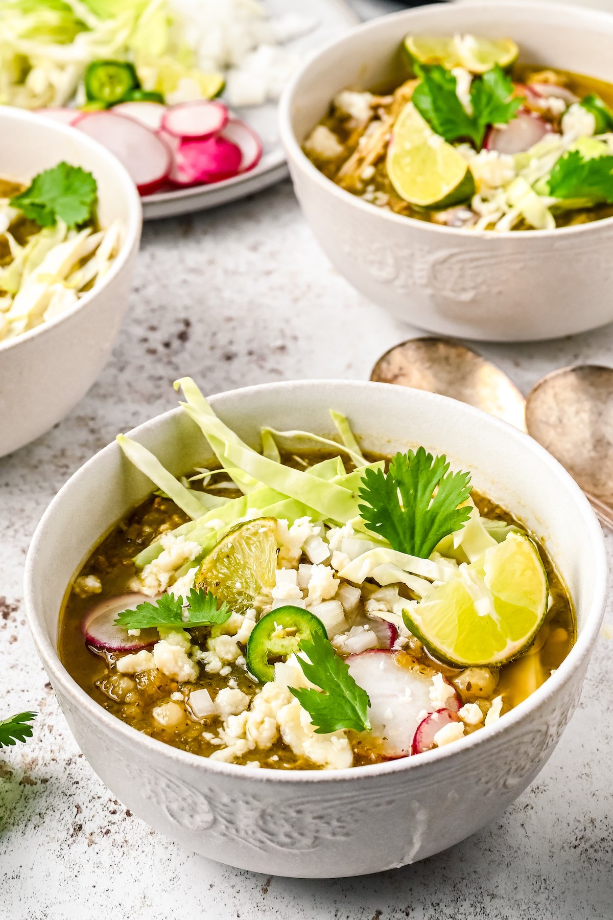 Two bowls of Mexican pozole with toppings.