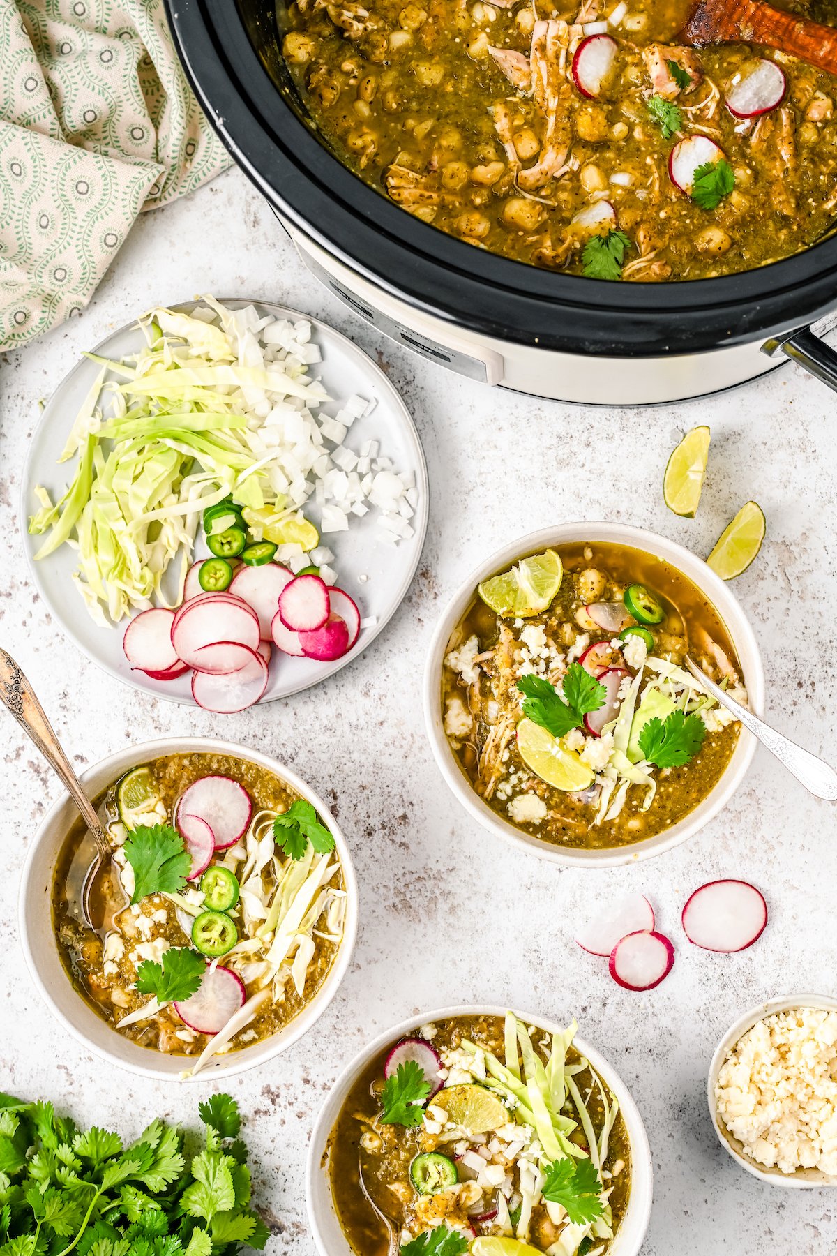 Two bowls of Mexican pozole with toppings on the side.