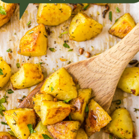 Roasted potatoes with herbs and garlic on a sheet pan lined with parchment paper.