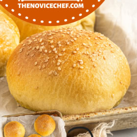 Homemade brioche buns with sesame seeds on top on parchment paper lined cookie sheet.