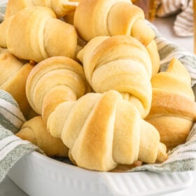 Golden-brown bread rolls in a bowl lined with a clean kitchen towel.