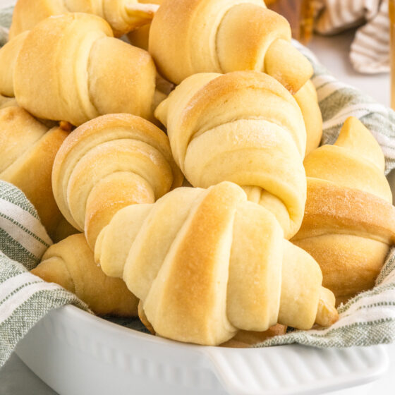 Golden-brown bread rolls in a bowl lined with a clean kitchen towel.