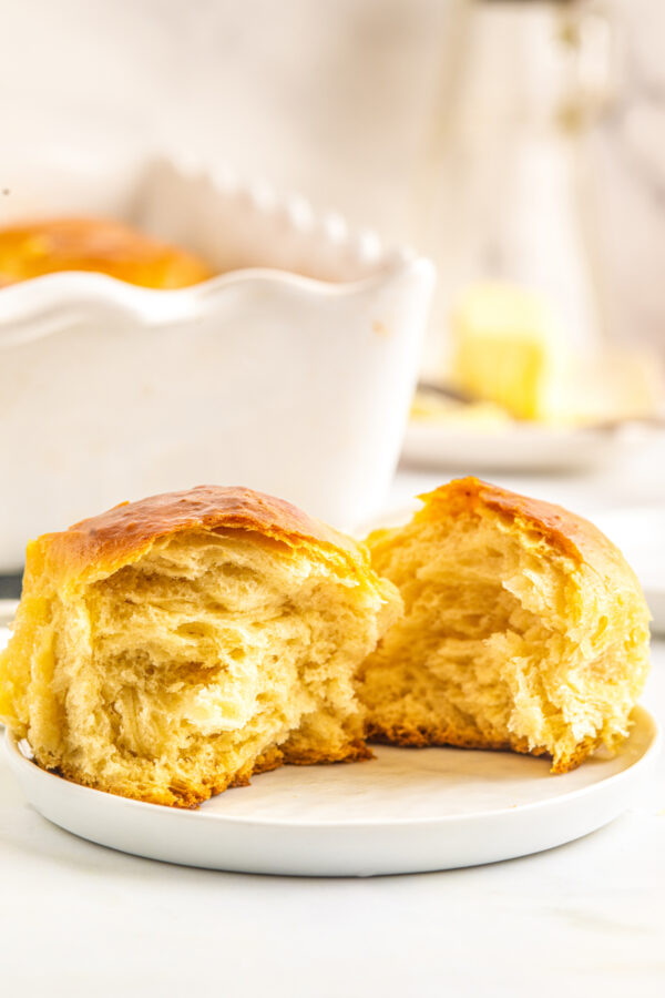 A sweet Hawaiian rolls torn in half on a plate to show the tender texture of the interior.
