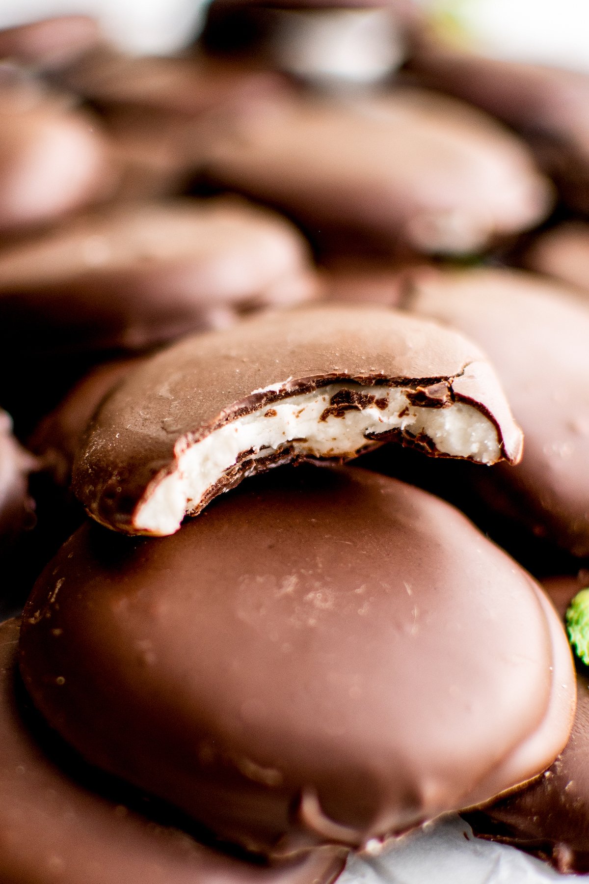 Peppermint patties. One has a bite taken from it to show the texture of the filling.
