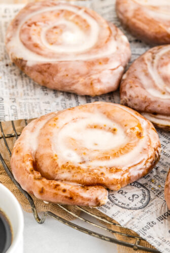 Hoememade honey buns with creamy glaze, on a cooling rack lined with parchment.